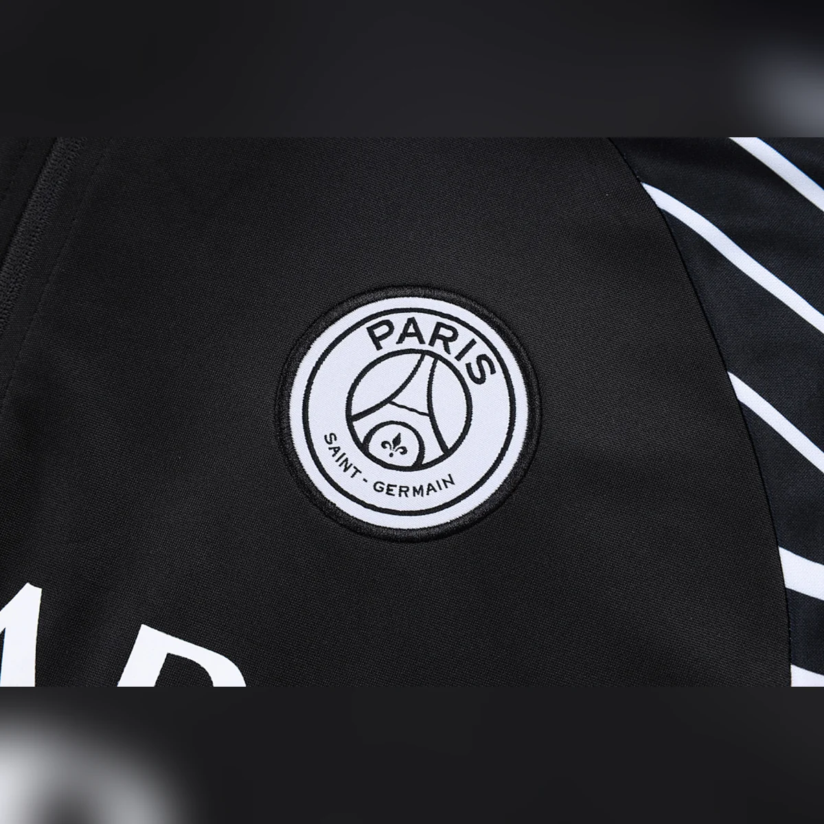 Chándal PSG Negro Jordan Media Cremallera 2025/26 – detalle del escudo y del logotipo Jordan