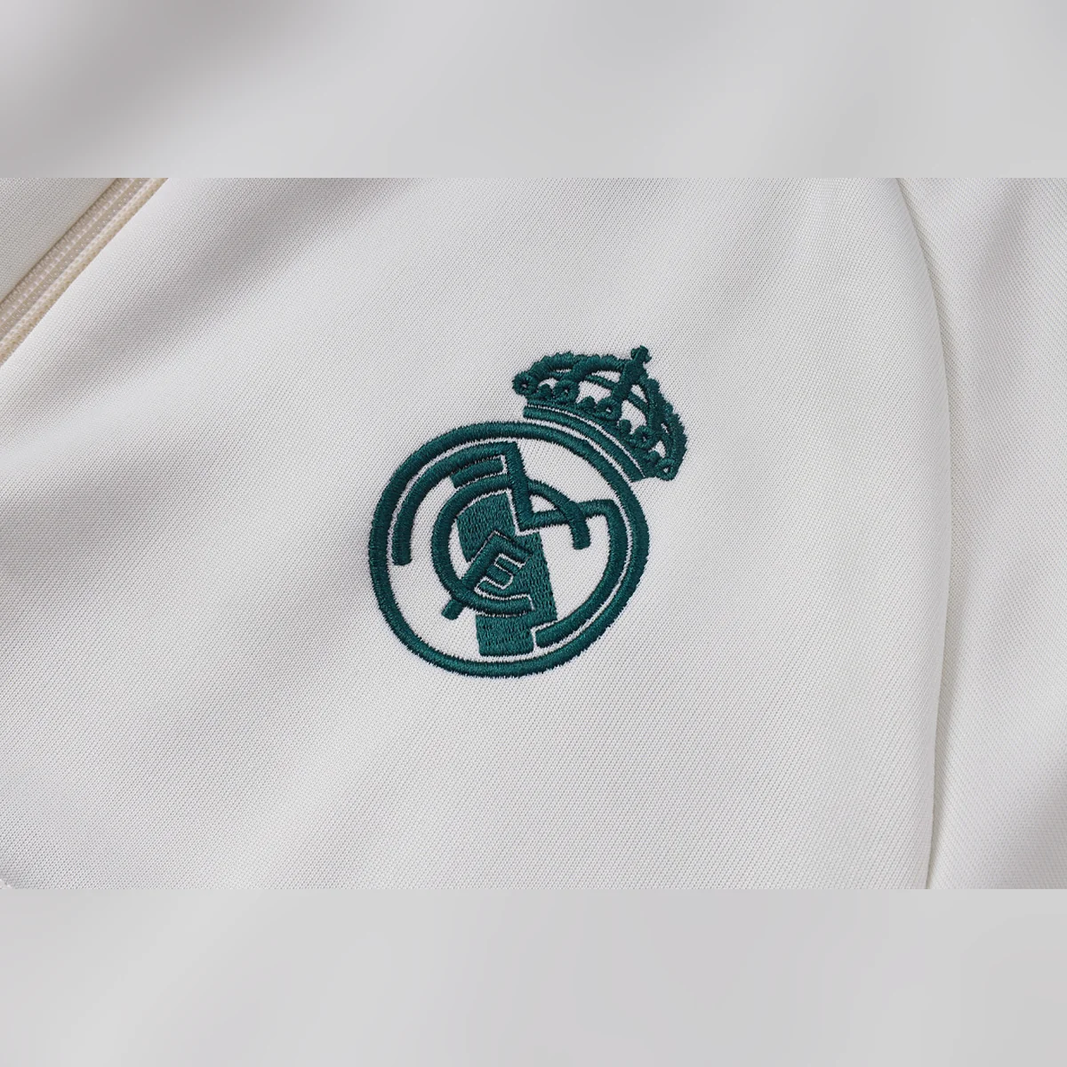 Chándal Real Madrid Beige con Franja Verde 2026/27 – detalle del escudo