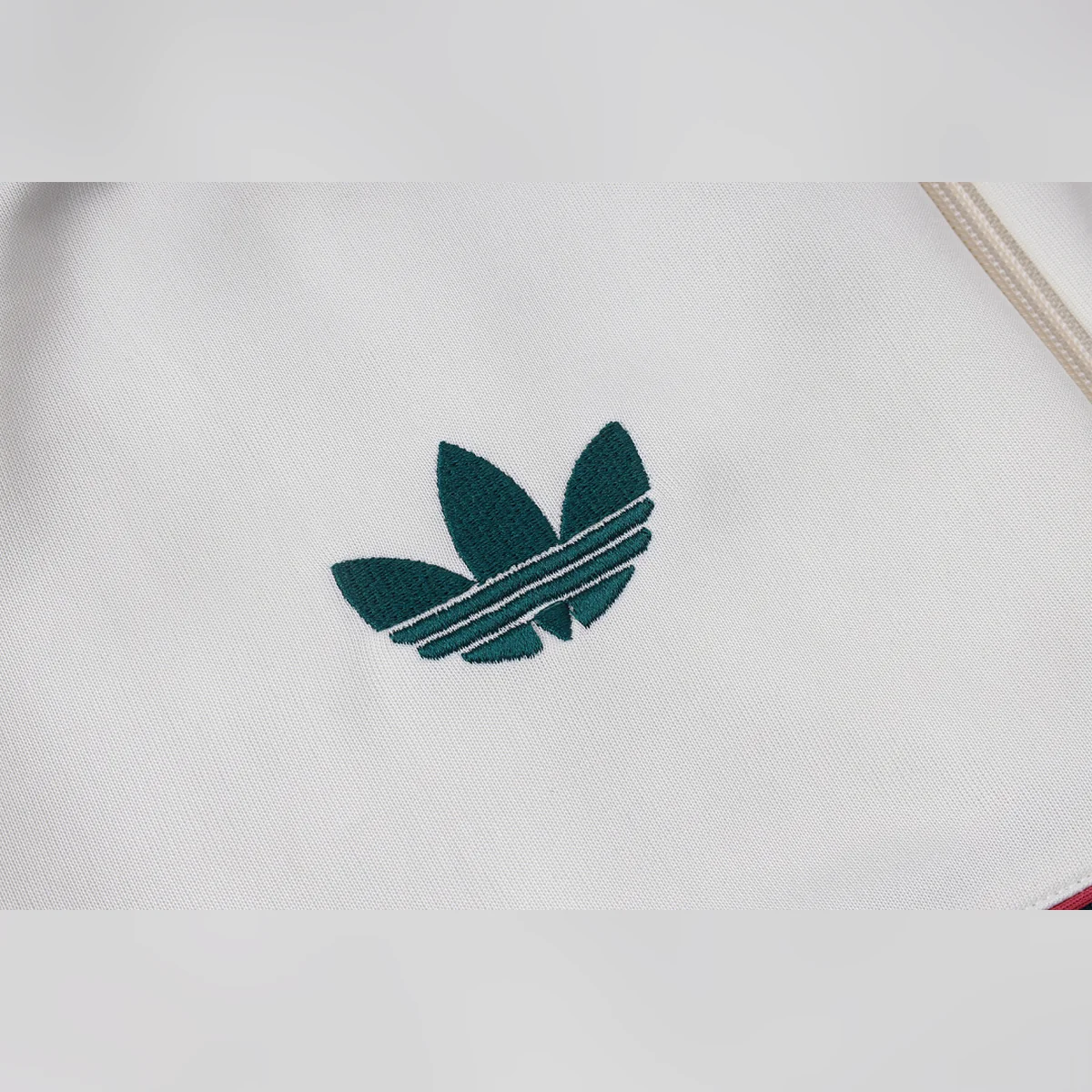Chándal Real Madrid Beige con Franja Verde 2026/27 – detalle del trébol de adidas