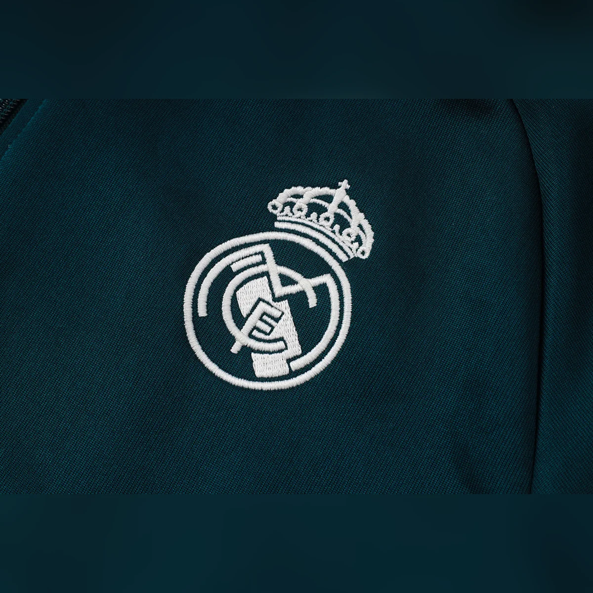Chándal Real Madrid Verde Oscuro Franja Blanca 2026/27 – detalle del escudo